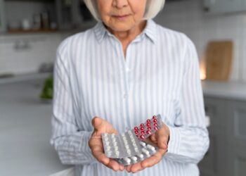 пожилая женщина держит в руках таблетки